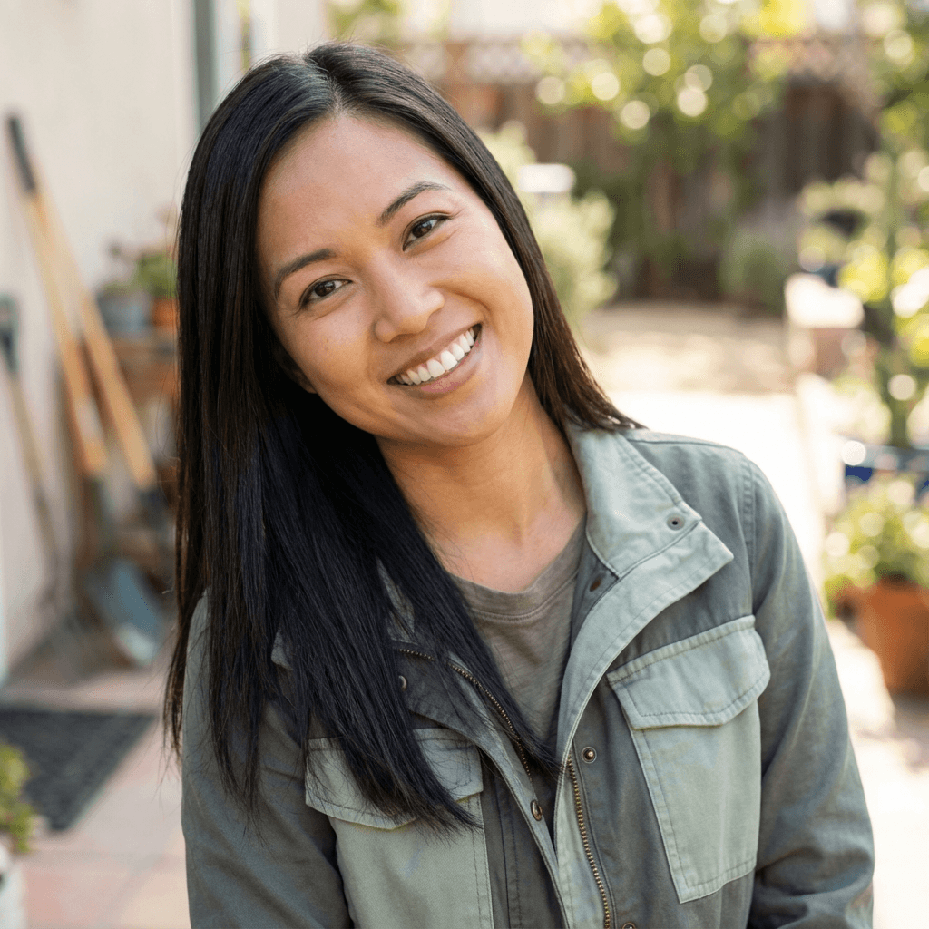 Female homeowner in her 50s smiling in front of a clean house